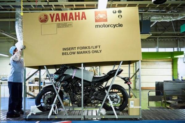 Yamaha motorcycle being placed in packaging for shipping.