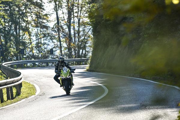 Aprilia RS660 shaded by trees while riding along a road