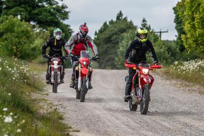 Three motorbikes riding along a green lane