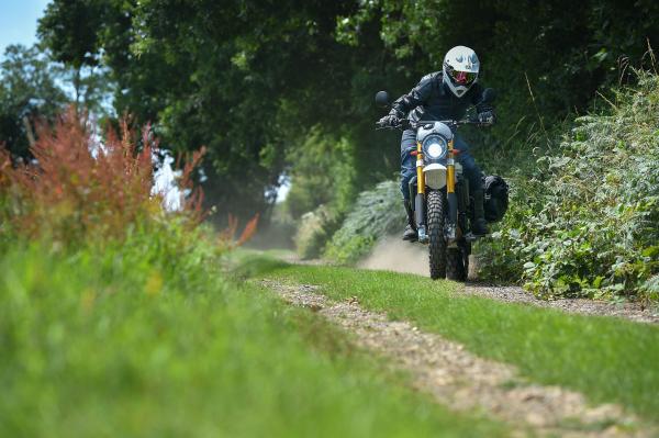 A motorcycle performs a power slide on a dirt road