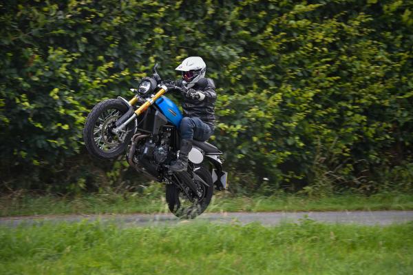 A motorcycle pulls a wheelie on a private road