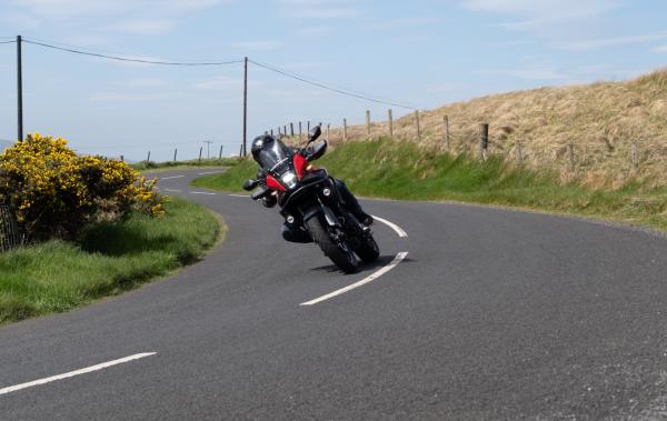 A motorbike riding through a corner on a country road